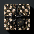 Luxury celestial star Christmas wrapping paper with a black satin bow, by Wrapped Studios.