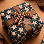 Elegant celestial star wrapping paper in navy and gold with a bronze ribbon, by Wrapped Studios.