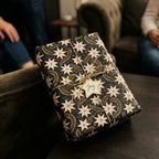 Luxury holiday gift wrap with starry poinsettia pattern and gold string bow by Wrapped Studios.