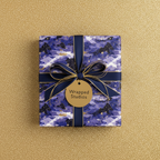 Elegant gift wrapped in luxury navy blue constellation wrapping paper with a gold ribbon bow.