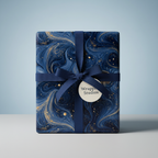 Elegant gift wrapped in navy marble wrapping paper with gold accents and a navy ribbon bow.