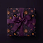 Luxury purple celestial wrapping paper with gold suns and a matching ribbon bow by Wrapped Studios.