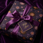 Luxury celestial purple gift wrap with gold sunbursts, satin bow, and gift tag by Wrapped Studios.