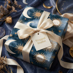 Celestial wrapping paper in navy and gold with a cream satin bow and Wrapped Studios gift tag.