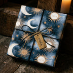 Celestial Christmas gift wrap with gold sun and moon pattern on navy blue paper by Wrapped Studios.