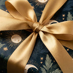 Luxury celestial wrapping paper with gold suns and moons and a gold satin bow by Wrapped Studios.