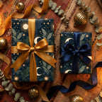 Celestial wrapping paper with gold moons on luxury navy holiday gift boxes by Wrapped Studios.