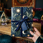 Luxury celestial wrapping paper with gold suns and moons, tied with a blue velvet bow by Wrapped Studios.