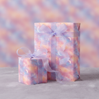 Two gifts wrapped in pastel celestial wrapping paper with sheer lavender ribbon on a fluffy surface.