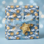 Celestial sun and moon wrapping paper on a gift with a blue organza bow and star tag by Wrapped Studios.