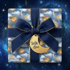Celestial wrapping paper with gold suns, navy ribbon, and a crescent moon tag by Wrapped Studios.