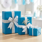 Three wrapped gifts in blue wrapping paper with silver and white ribbons, perfect for baby shower or birthday presents.