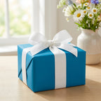 Teal gift box wrapped in solid color paper with white ribbon bow, perfect for birthday or any occasion.