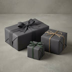 Three gray gift boxes with decorative ribbons on a neutral background. Charcoal gift wrap.
