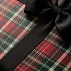 Red and green tartan plaid Christmas wrapping paper with a black ribbon by Wrapped Studios.