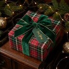 Red and green plaid wrapping paper with a velvet bow, luxury Christmas gift wrap by Wrapped Studios.