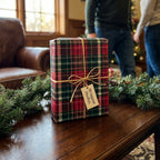 Red and green plaid Christmas gift wrap by Wrapped Studios with gold twine on a cozy holiday table.
