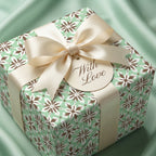 Sage green floral wrapping paper from Wrapped Studios, with a cream satin bow and "With Love" gift tag.