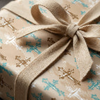 Rustic baptism wrapping paper with teal and gold crosses and a cream woven ribbon bow by Wrapped Studios.