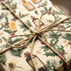Vintage Christmas gift wrap with apothecary and pine pattern, tied with rustic twine by Wrapped Studios.