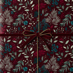 Burgundy floral wrapping paper with velvet ribbon and gold string, ideal for elegant gifts.