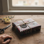 Elegant floral wrapping paper in maroon and teal, tied with twine and a "Wrapped Studios" tag.