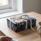 Elegant gift wrapped in navy floral wrapping paper with lace ribbon and a "Merci" tag.