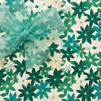 Elegant floral wrapping paper in green and cream tones, tied with a sheer turquoise ribbon.