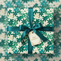 Square gift wrapped in green floral wrapping paper with satin ribbon bow and “Happy Celebrations” tag.