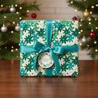 Elegant Christmas gift wrapped in floral paper with a teal satin ribbon and bow, with a Christmas tree in background.