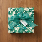 Square gift wrapped in floral wrapping paper with a sheer green ribbon, bow, and "A Special Gift" tag.