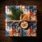 Christmas gift wrapped in cityscape paper with twine, evergreen sprig, and orange slice. Wrapped Studios.