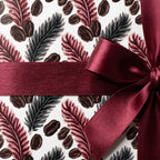 Elegant coffee bean and botanical wrapping paper with a burgundy satin bow by Wrapped Studios.