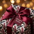 Luxury Christmas gift wrap with botanical pine pattern and burgundy satin ribbon by Wrapped Studios.