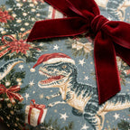 Dinosaur Christmas wrapping paper with a T-Rex in a Santa hat and red velvet ribbon by Wrapped Studios.
