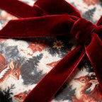 Whimsical Christmas gift wrap with red dragons and a velvet ribbon by Wrapped Studios.
