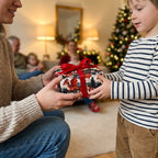 A child receives a holiday gift in dragon Christmas wrapping paper with a red ribbon by Wrapped Studios.
