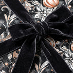 Elegant floral wrapping paper in dark tones with a luxurious black velvet bow.