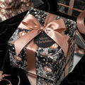 Elegant Christmas wrapping paper featuring ornament design with copper ribbon and tag.