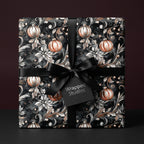 Elegant Christmas gift wrap by Wrapped Studios, featuring floral and ornament pattern with a black satin ribbon.