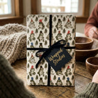 Whimsical frog Christmas wrapping paper with a black velvet ribbon by Wrapped Studios on a cozy table.
