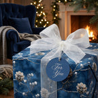 Navy floral wrapping paper with sheer white ribbon, gift tag, in a cozy Christmas setting.