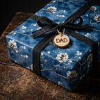 Wrapped gift with navy floral wrapping paper, black ribbon, and "DAD" tag.