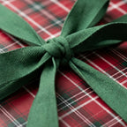 Red plaid Christmas gift wrap with a green fabric ribbon bow by Wrapped Studios.