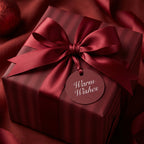 Elegant, square gift wrapped in striped burgundy paper with a satin ribbon bow and a "Warm Wishes" tag.