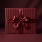 Elegant striped wrapping paper in deep red with a satin bow on a square gift box.