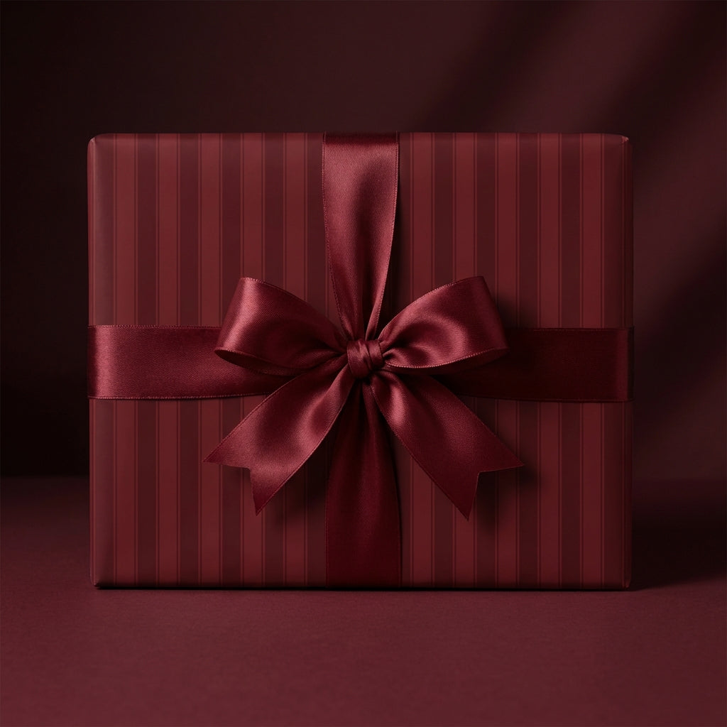 Elegant striped wrapping paper in deep red with a satin bow on a square gift box.