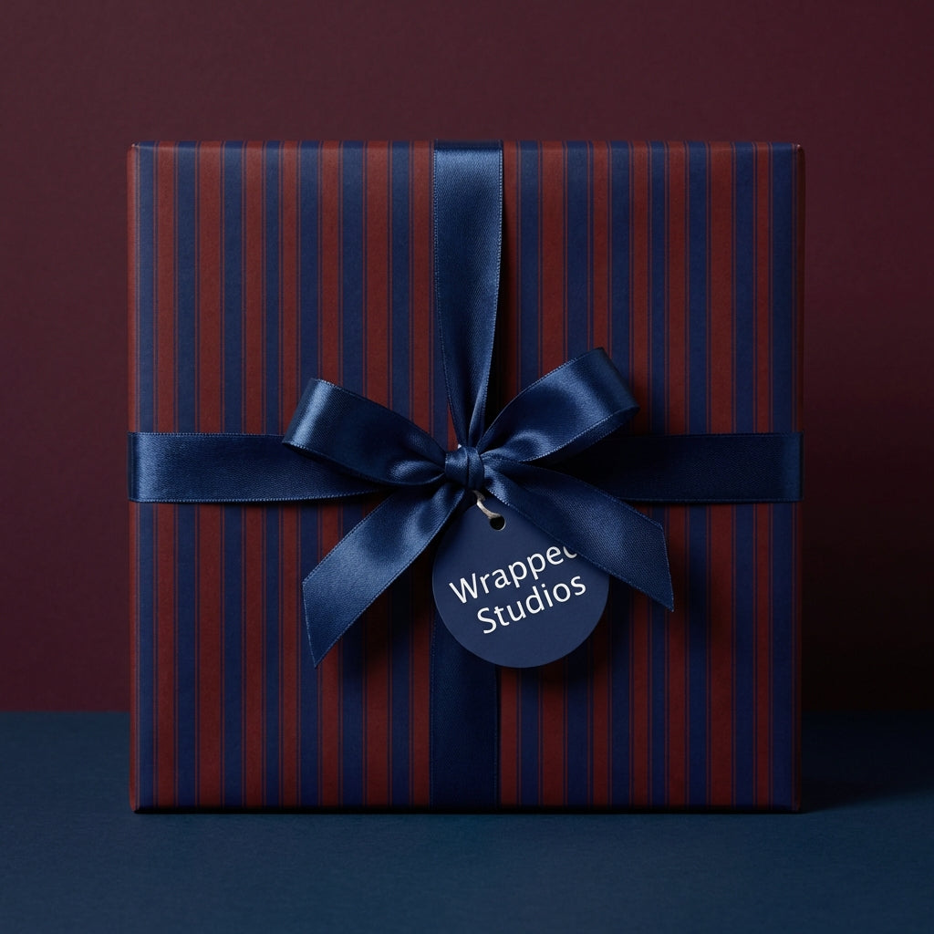 Elegant square gift box wrapped in navy and burgundy striped wrapping paper with a satin navy bow.
