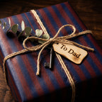 Striped father's day wrapping paper with twine bow, eucalyptus, and "To Dad" tag.