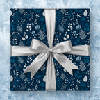 Navy blue gift wrapped in elegant floral Christmas wrapping paper with a silver bow.